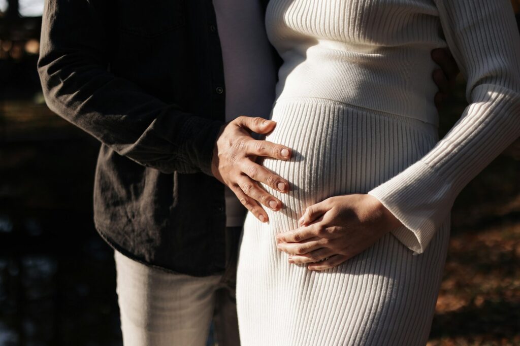 Family day. Stylish unrecognisable marriage pregnant couple waiting for baby. Man is hugging